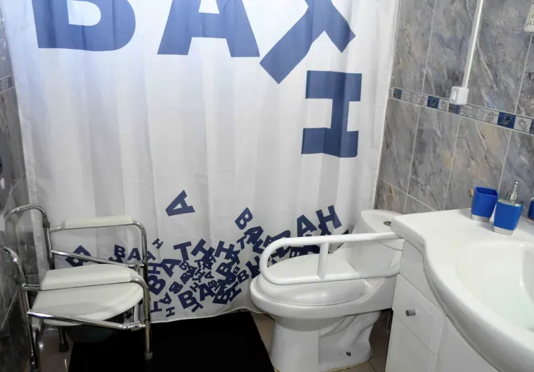 Baño con silla de ducha y barras de apoyo